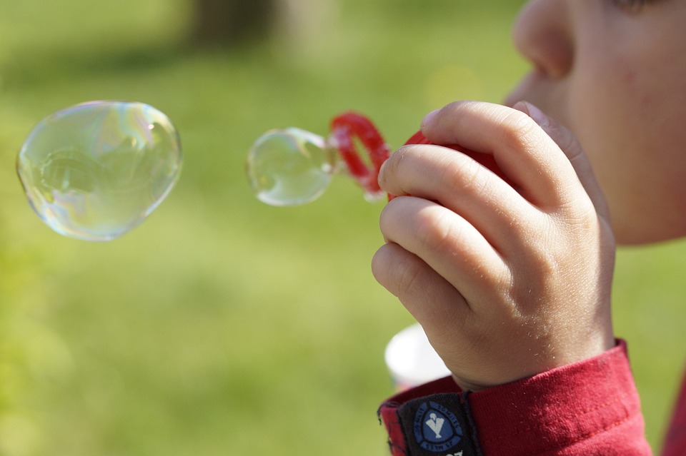 child blowing bubbles at a field